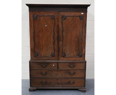 A George III Chippendale period mahogany linen press, the blind fretwork pediment above a pair of doors with applied foliate 