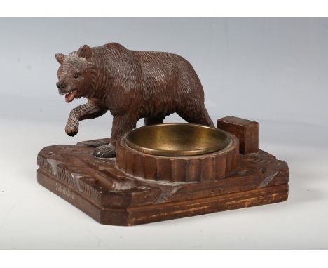 An early 20th century Black Forest carved softwood pipe smoker's compendium, mounted with a prowling bear, height 12cm, width