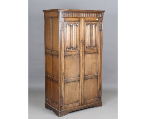 A mid-20th century Jacobean Revival oak wardrobe, the two panelled doors carved with linenfold, height 178cm, width 96cm, dep