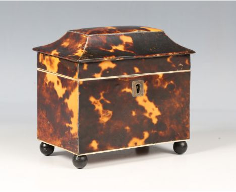 An early 19th century tortoiseshell tea caddy of sarcophagus form, raised on spherical ebonized feet, height 12cm, width 13.2