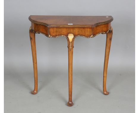 A mid-20th century walnut and gilded demi-lune side table with carved shell details, height 76cm, width 75cm, depth 34cm.Buye