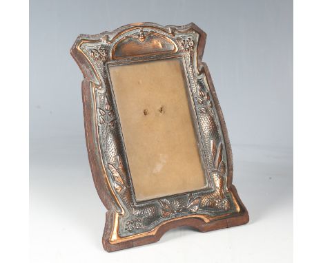 An early 20th century Arts and Crafts pressed copper photograph frame, decorated in relief with butterflies and flowering ste