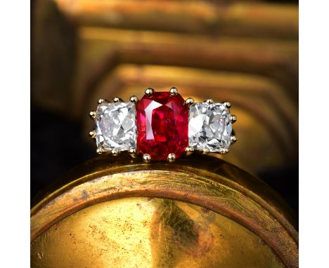 Featuring a centered rectangular-cut ruby, weighing 2.34 carats, flanked by two antique cushion-shaped diamonds, one weighing