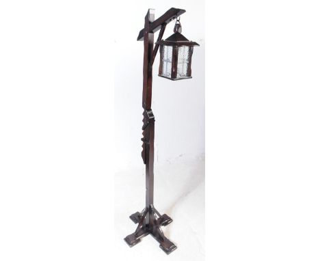 A 20th century oak wood floor standing lantern standard lamp. The lamp raised on four block feet, raised through an adjustabl