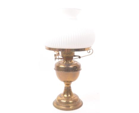 A 20th century Victorian Revival brass oil lamp. The lamp raised on a rounded stepped base, having scrolled supports holding 