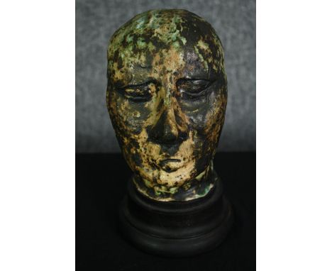 A ceramic glazed bust; man's head on ebonised socle. H.23cm. 