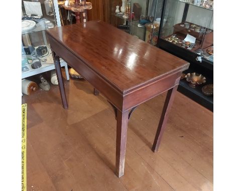 A Georgian mahogany fold over card table, the cantilevered structure supports with arched detail on square chamfered supports