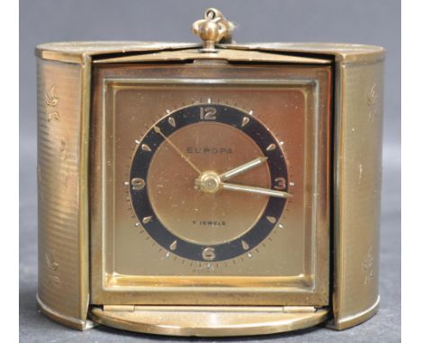 A mid century Europa travel alarm clock, the gilt metal oval case with engine turned foliate decoration, opening on a retract