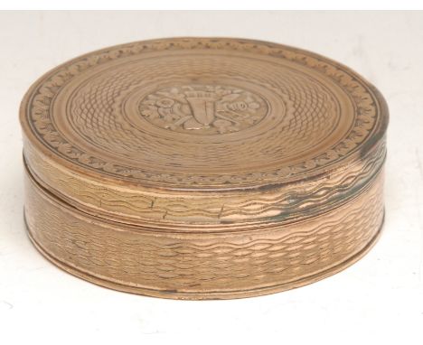 A late 18th century gilt copper circular snuff box, engine turned and chased with triumphal regalia, 7.5cm diam, c.1790 