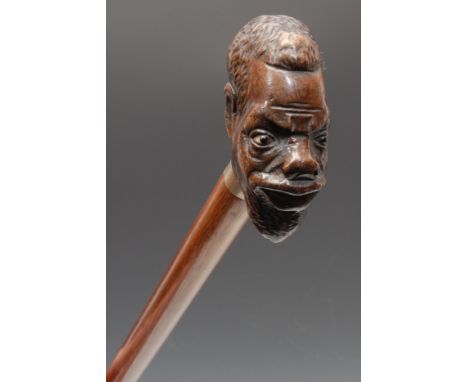 An early 20th century novelty walking stick, the pommel carved as the head of a man of African descent, hardwood cane, 91.5cm