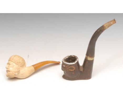An African pipe, the bowl carved as a tribal mask, the features picked out in metal, 16cm long overall; a German meerschaum p