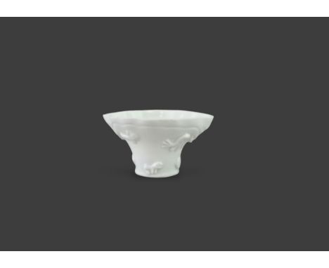 A 'blanc de chine' Libation cup, Kangxi, applied to one side with a flying crane and a  ram,  the other with a dragon head an