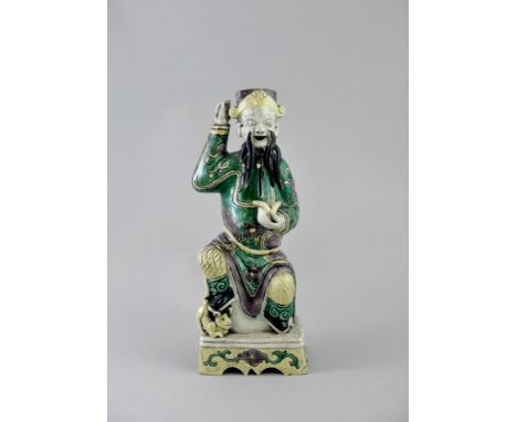 A 'famille verte' Biscuit seated Guan Yu, Kangxi, the bearded God of War with fierce expression, holding an ingot in one hand