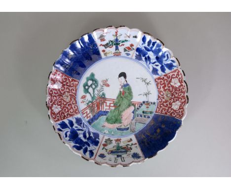 A 'Famille Verte' Plate with a Beauty, Kangxi, of circular shape with petal led rim, a lady sitting in a garden painted in th