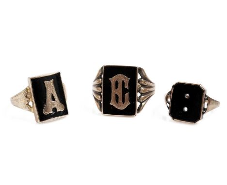 Two black onyx and yellow gold monogrammed signet rings, each with rectangular onyx plaque, each overlaid with an initial, le