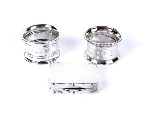 An antique silver snuff box, of shaped rectangular form; and two silver napkin rings. (3)