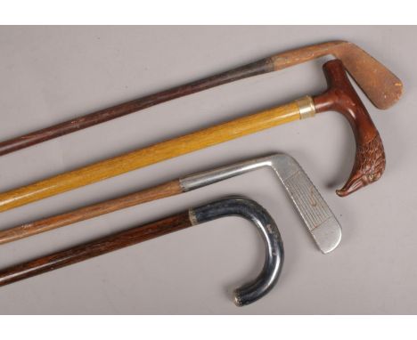 Two walking sticks along with two wooden shaft golf clubs. One stick with bird of prey handle.  