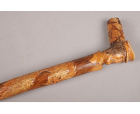 A carved wooden oriental stick. With dragon and mask decoration.  