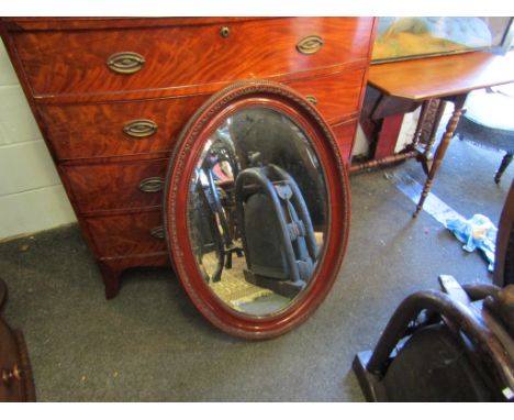 A mahogany effect oval bevel edged mirror, 88cm high x 61cm wide            
