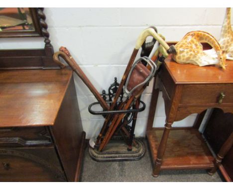 A cast iron umbrella stand with assorted walking sticks, shooting stick etc.