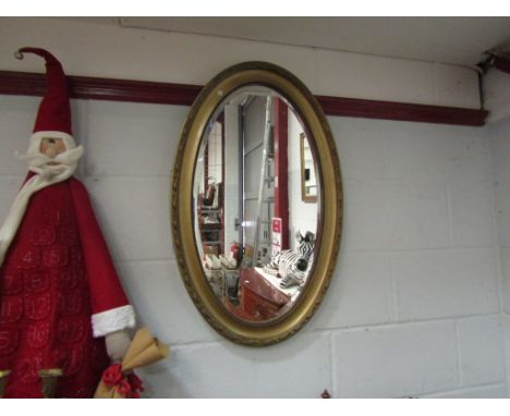 An oval bevel edged gilt framed mirror, 80cm x 50cm total
