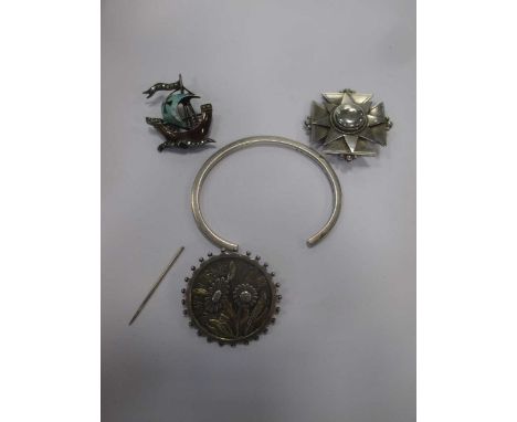 Three white metal brooches, one with enamel and paste decoration, and a bangle (4)