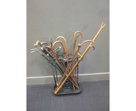 A cast iron stick stand containing assorted walking sticks, one silver mounted, riding crops, golf clubs and shooting sticks