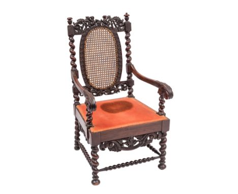 A Charles II walnut and canework elbow chair, circa 1680; the backrest toprail openwork carved with confronting amorini issui