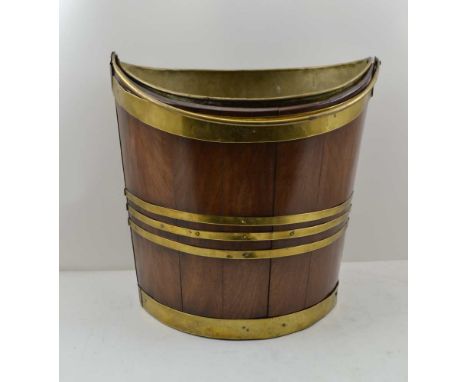 AN EARLY 19TH CENTURY IRISH MAHOGANY PEAT BUCKET of elliptical form, coopered construction, with brass bands, over swing hand
