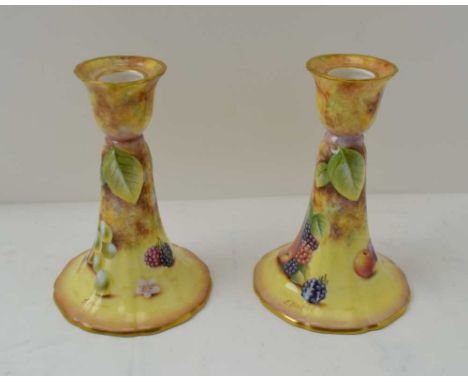 A PAIR OF ROYAL WORCESTER BONE CHINA CANDLESTICKS, hand painted fruit decoration, signed by J. Bowman, printed factory backst