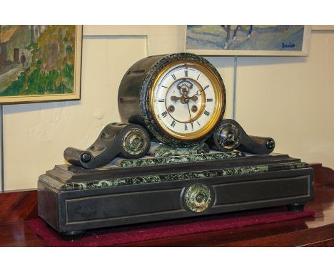 A Victorian slate mantel clock with white enamel and brass dial, in drum shape case with scroll supports, on rectangular base