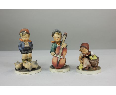 Three Goebel Hummel figures comprising boy with pigs 'Farm Boy', boy playing an instrument 'Sweet Music', and girl with chick