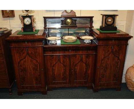 A Regency mahogany sideboard with inverted break-front top and raised mirror back, the base with drawer and cupboard below en