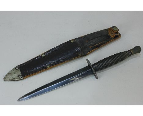 A Fairbairn - Sykes fighting knife with ridged grip and plain 16.5cm blade, in leather scabbard