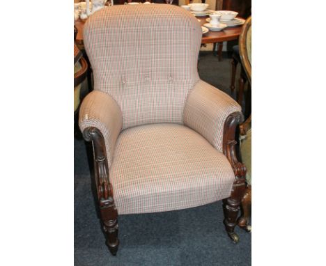A Victorian rosewood button back upholstered armchair, with scroll carved arms, on baluster turned front legs and castors