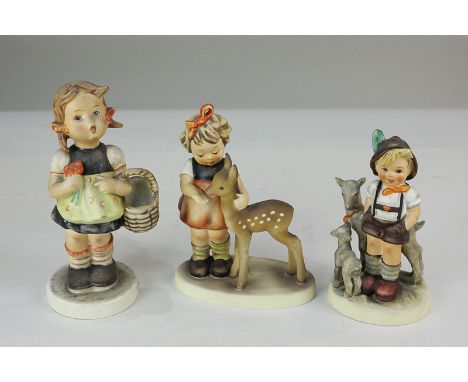 Three Goebel Hummel figures comprising girl with basket holding a posy, girl with fawn, and boy with goats, tallest 15.5cm