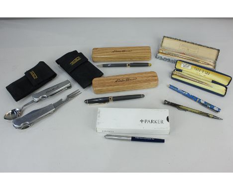 An Eddie Bauer ball point pen with matching propelling pencil in wooden boxes, two Eddie Bauer folding knife, fork and spoon 