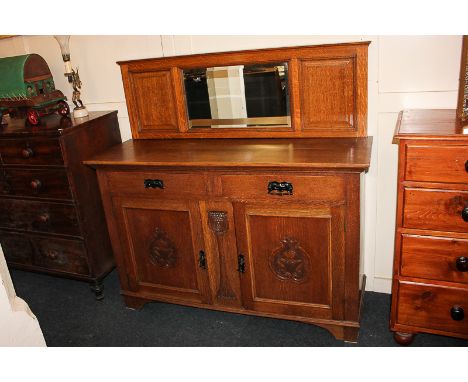An Arts and Crafts oak sideboard with later mirror back, rectangular top with two drawers and two panel doors carved with sin