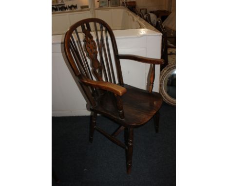 A Windsor elbow chair with central pierced wheel and stick back, on turned legs