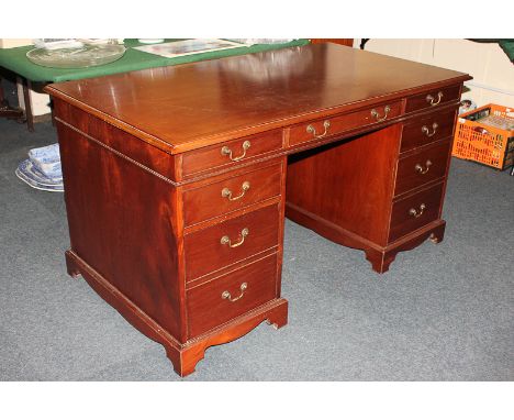 An Edwardian style mahogany desk, the rectangular top with inlaid border, an arrangement of seven drawers below, on bracket f