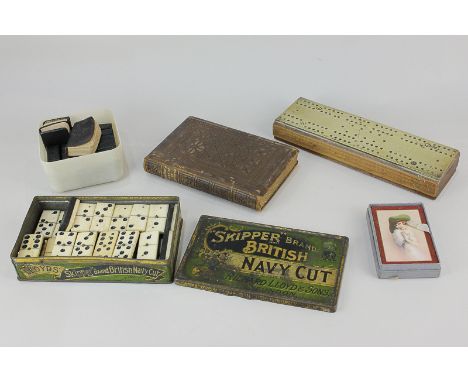 A set of bone and ebony dominoes, a brass mounted cribbage board, a pack of playing cards depicting a 1920's lady, Felicia He