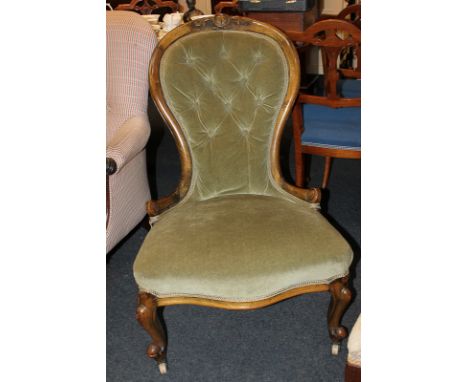 A Victorian mahogany framed button back nursing chair with foliate carved surmount and green upholstery, on cabriole front le