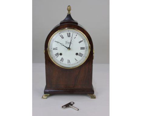 A Comitti of London mahogany mantel clock, the circular white enamel dial with Roman numerals, the movement striking on a bel