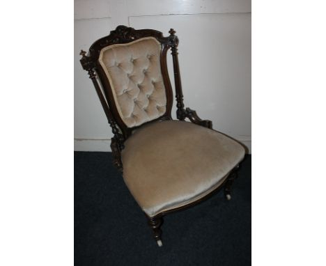 A Victorian low seat drawing room chair with floral carved surmount, button upholstered back and padded seat, on turned and f