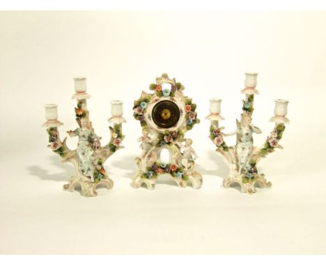 A late 19th century continental clock garniture comprising a clock with applied cherub and floral encrusted decoration raised