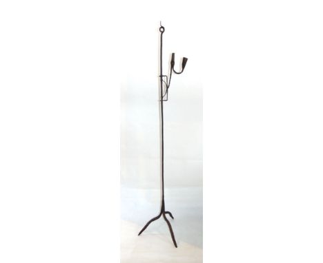 An antique wrought iron floor standing rush light with pigs tail finial and tripod supports