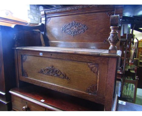 An early 20th century oak hall bench, the rectangular panelled back with applied mouldings over down swept and rolled open ar