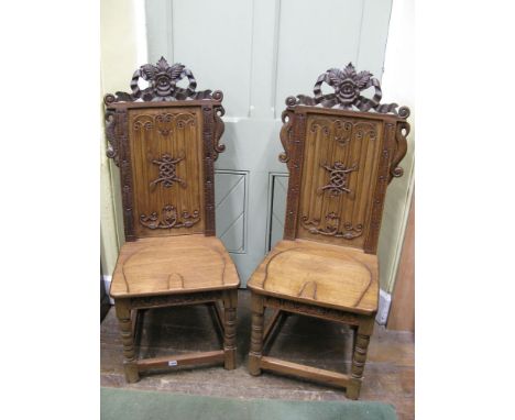 A pair of Old English style hall chairs with carved linen fold panelled backs within carved frames with raised tied ribbon, f