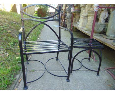 An iron framed garden armchair and matching stool together with an iron obelisk.