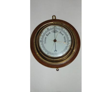 An marine barometer in a brass case with enamel dial